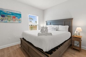 A bedroom with a bed, a nightstand, a window with blinds, and a painting on the wall. - Windmark Coastal Paradise 5BR/5BA, private Pool, sleeps 18, pet friendly, 2 golf carts (Port St. Joe)