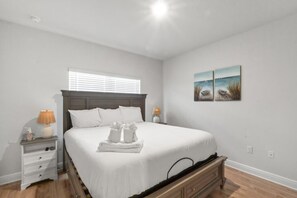A bedroom with a bed, bedside tables, a dresser, and artwork on the wall. - Windmark Coastal Paradise 5BR/5BA, private Pool, sleeps 18, pet friendly, 2 golf carts (Port St. Joe)