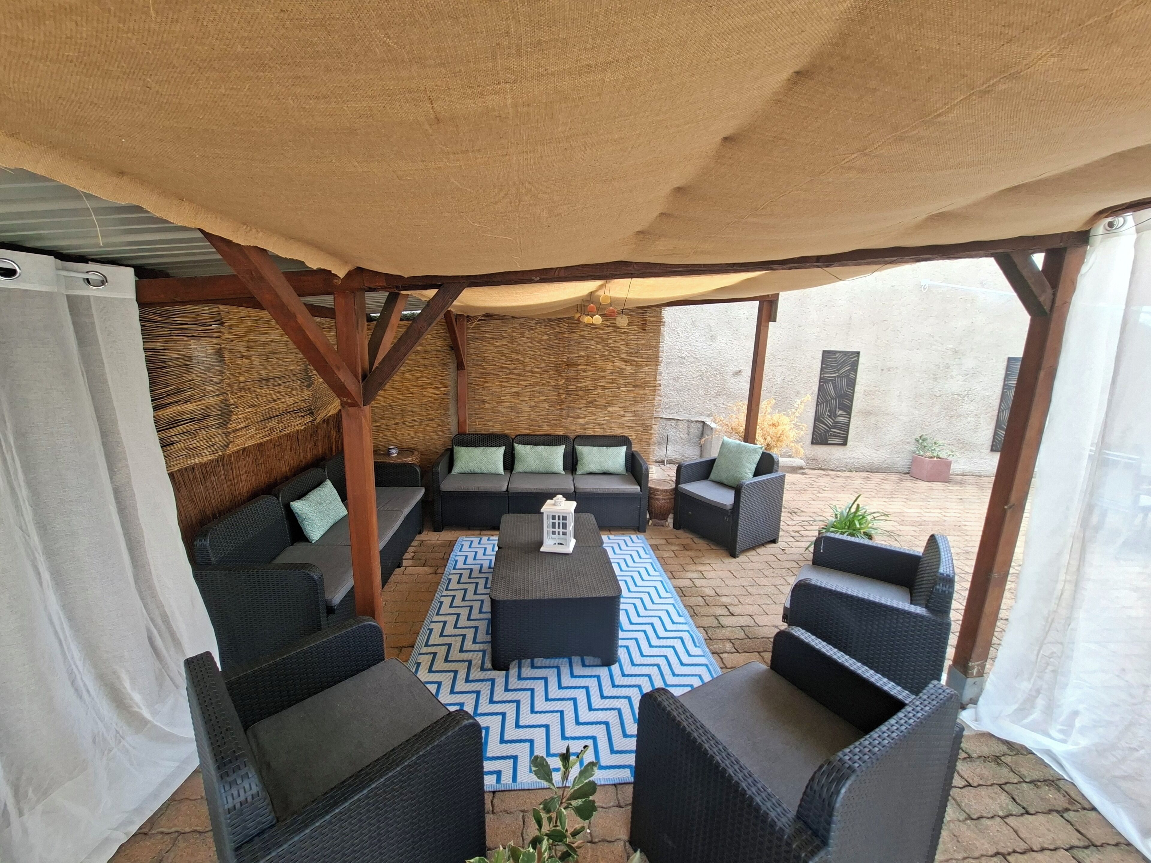An outdoor seating area with wicker furniture and a patterned rug.