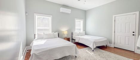 A bedroom with two beds, a ceiling fan, and a large window.