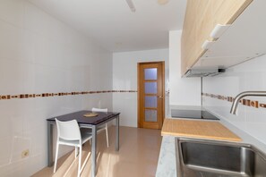 A compact kitchen with a dining area, a wooden door, and a stainless steel sink. - Volvoreta Valdoviño Apartment (Valdoviño)