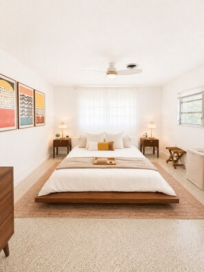Een slaapkamer met een bed, nachtkastjes, een raam en kunst aan de muur.