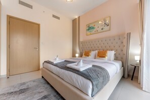 Une chambre d’hôtel avec un grand lit, une porte en bois, un tableau au mur et une petite table avec une lampe.
