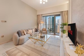 A modern living room with a sofa, coffee table, and a flat-screen TV. - Walk to Dubai Mall and Dubai Fountain Parking Pool (Dubai)