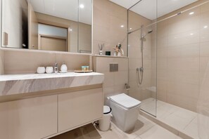 Une salle de bain moderne avec une douche à parois de verre, un meuble-lavabo en marbre et des toilettes.