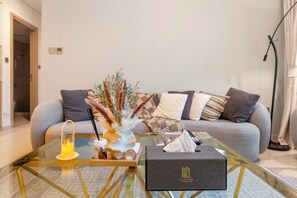A modern living room with a glass coffee table, a sofa with patterned cushions, and a decorative vase with dried plants. - Walk to Dubai Mall and Dubai Fountain Parking Pool (Dubai)