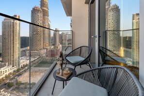 A balcony with two wicker chairs, a small table, and a vase with dried flowers. - Walk to Dubai Mall and Dubai Fountain Parking Pool (Dubai)