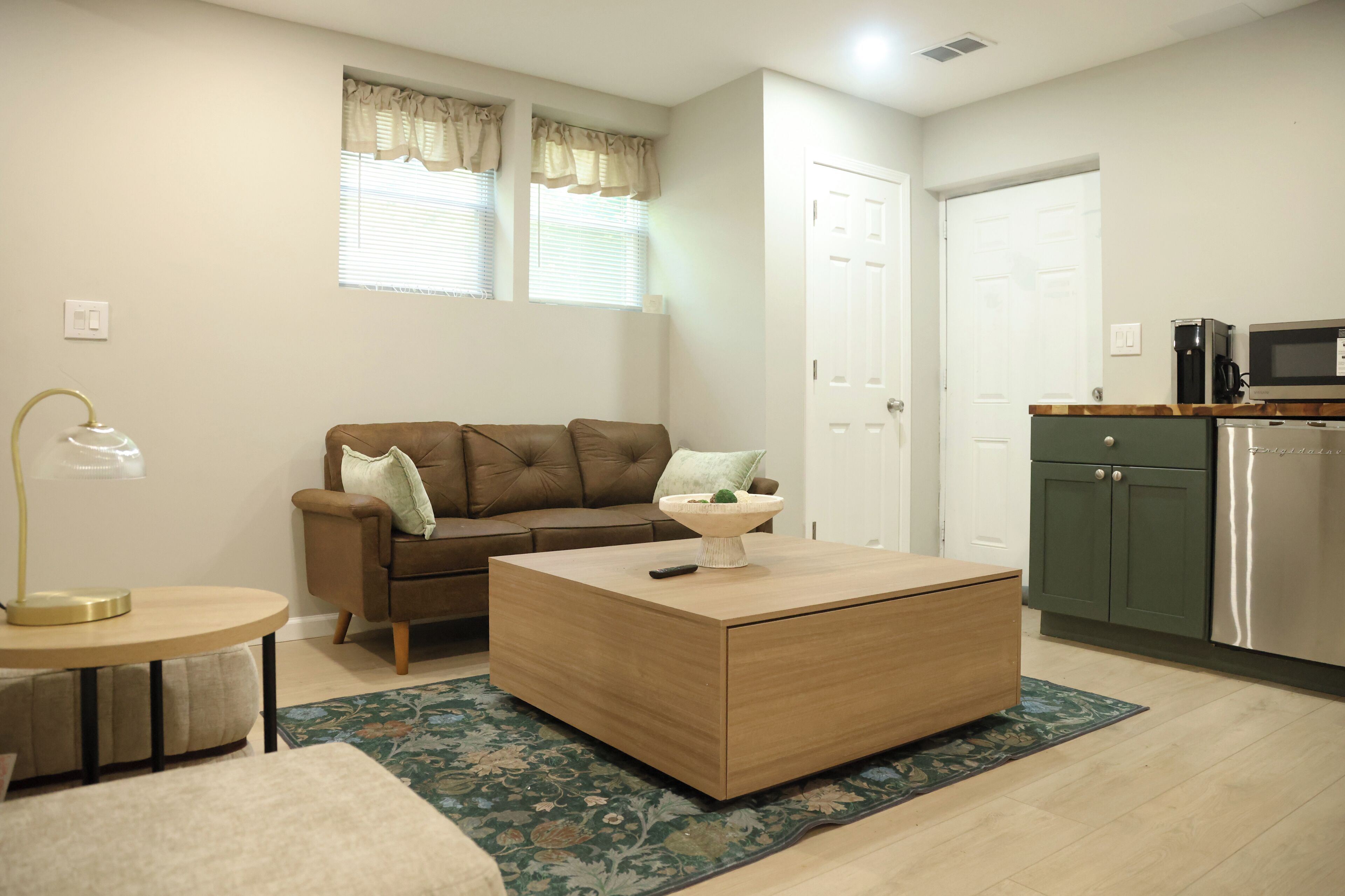 A living room with a brown sofa, a coffee table, a lamp, and a patterned rug.