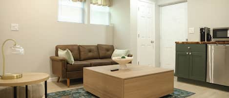 A living room with a brown sofa, a coffee table, a lamp, and a patterned rug.