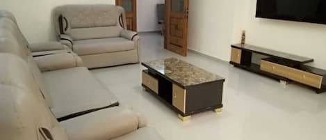 A living room with a sofa, a coffee table, and a TV stand.