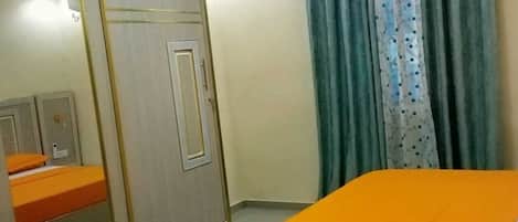 A bedroom with a bed, a wardrobe, and a mirror.
