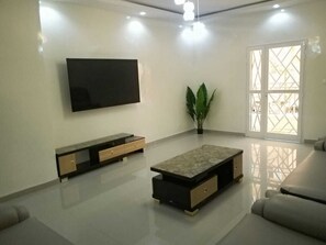 A modern living room with a flat-screen TV, a low coffee table, and a sofa.
