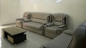 Un soggiorno moderno con un divano angolare beige, un poggiapiedi coordinato e illuminazione a soffitto.