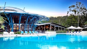 A swimming pool with lounge chairs and a covered area with tables and umbrellas.