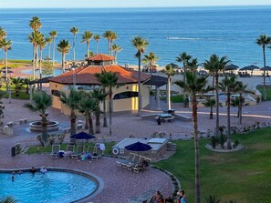 A resort with a pool, lounge chairs, palm trees, and a view of the ocean. - 2BDR Remodeled penthouse / Sandy Beach+ beach gear (Puerto Peñasco)