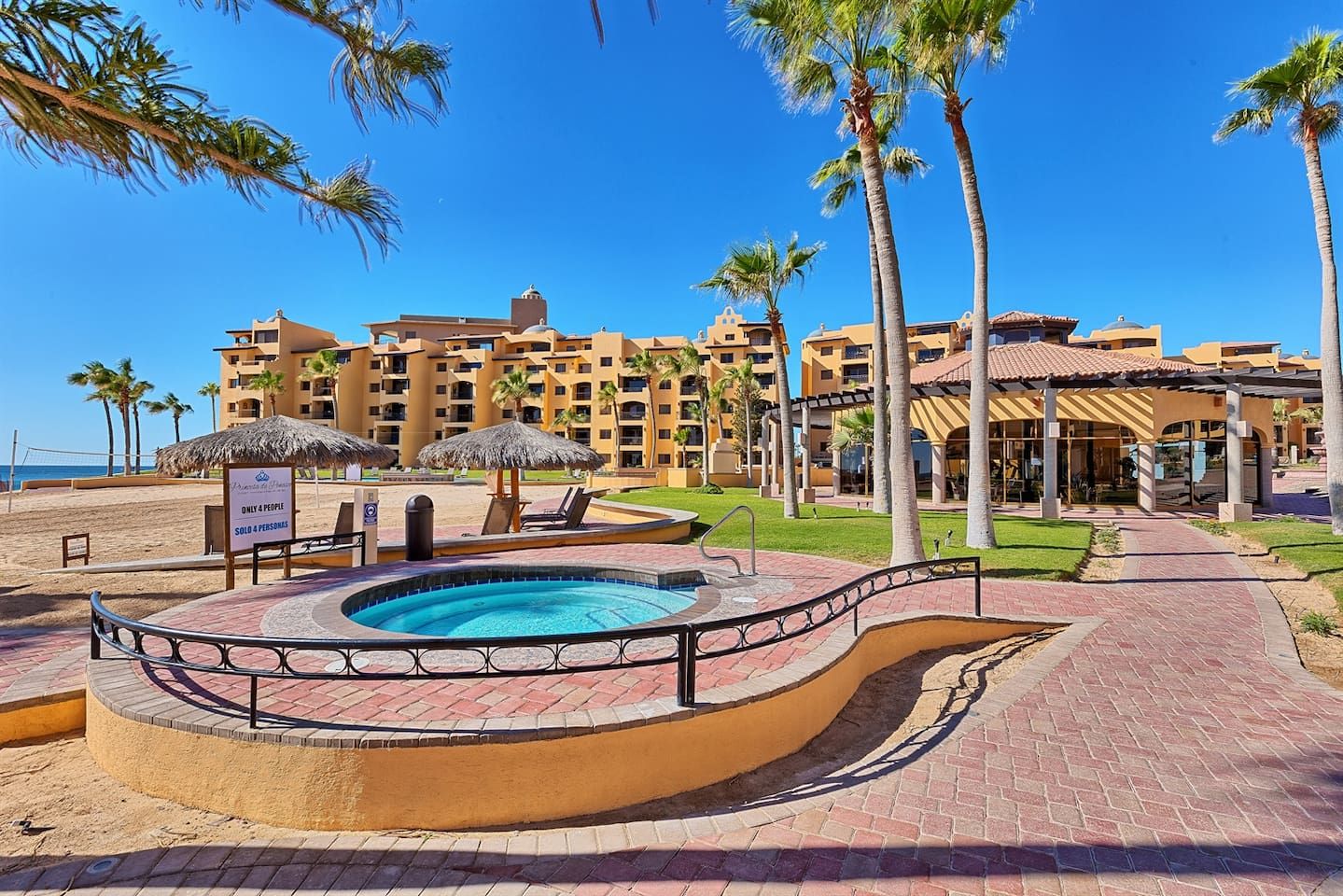 Ein Resort mit Swimmingpool, Palmen und Blick auf den Strand.