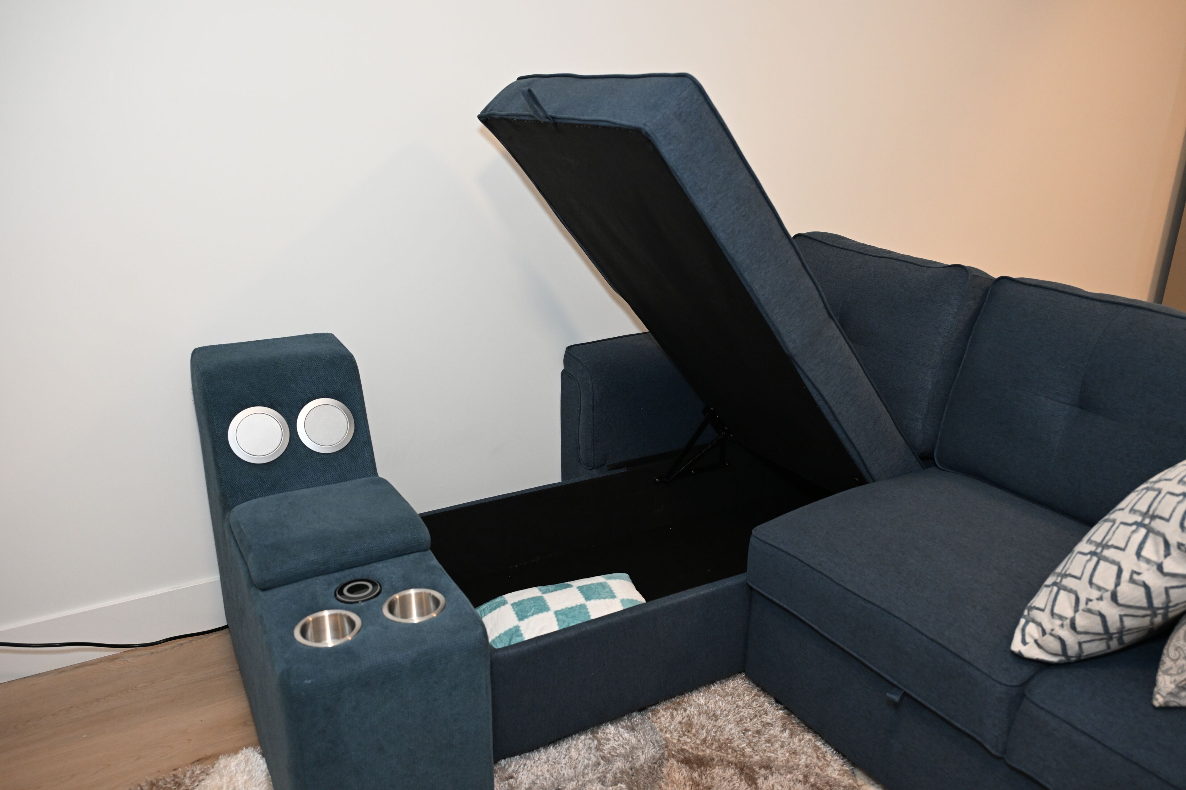 Une pièce avec un canapé bleu, une petite table sur laquelle reposent deux objets ronds, et un coussin à motifs.