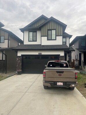 A residential driveway with a pickup truck parked in front of a two-story house with a garage. - Luxury 2BR Apartment | Relax, Unwind, Indulge (Edmonton)