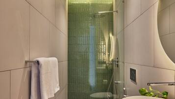 A modern bathroom with a glass-enclosed shower, a white sink, and a towel rack.