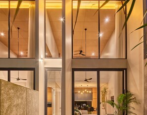 Un intérieur moderne avec un escalier, des ventilateurs de plafond et un coin repas.