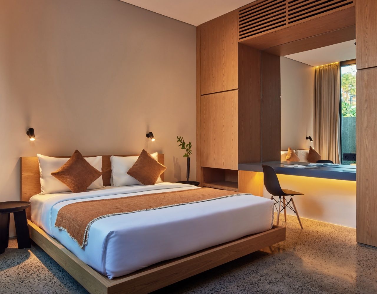 A modern bedroom with a large bed, bedside tables, a desk, and a mirror.