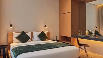 A modern hotel room with a bed, bedside tables, a desk, and a mirror.