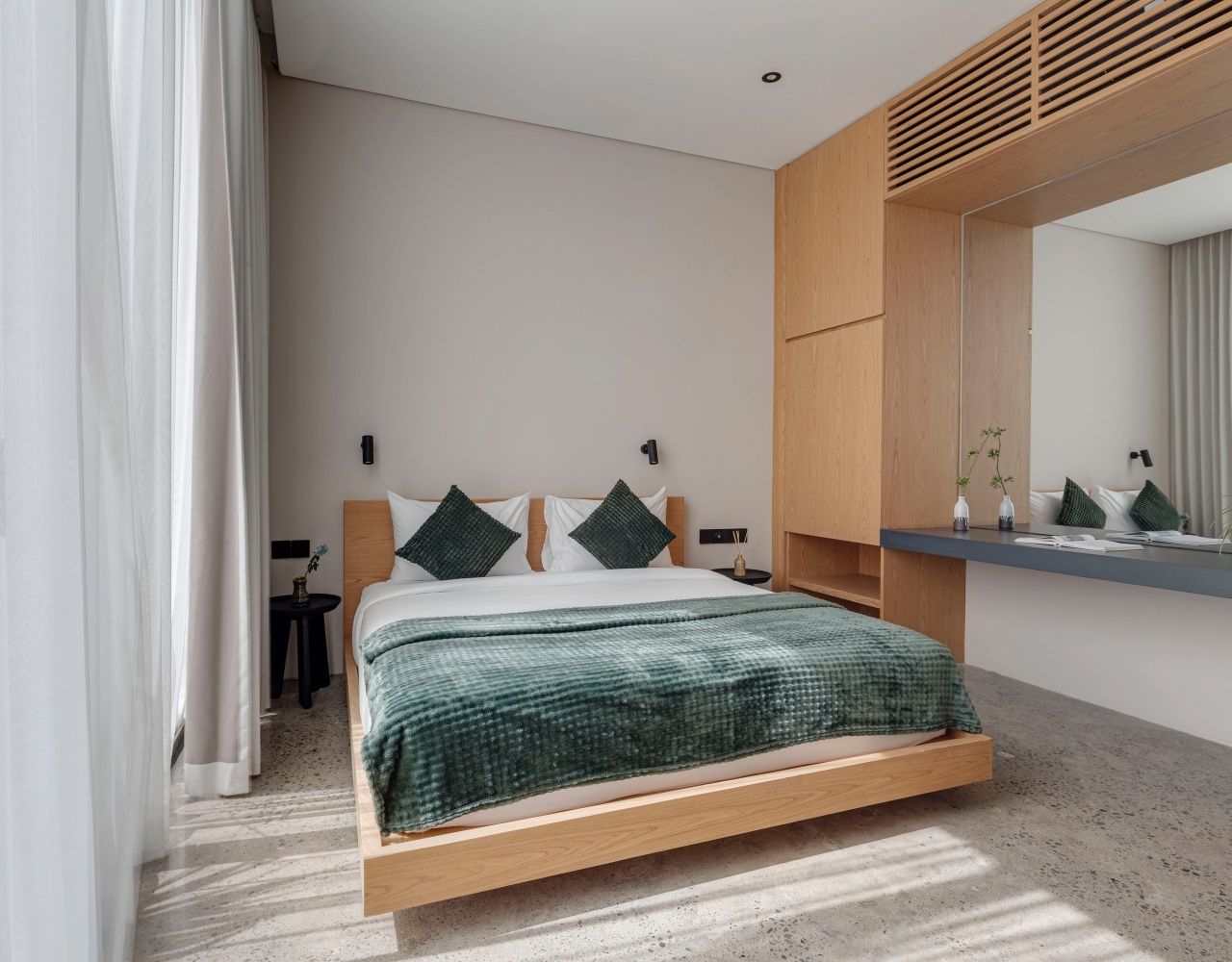 Een moderne slaapkamer met een houten bedframe, een grote spiegel en een klein nachtkastje.