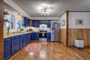 Una cocina con armarios azules, piso de madera, una isla central y una lámpara en el techo.
