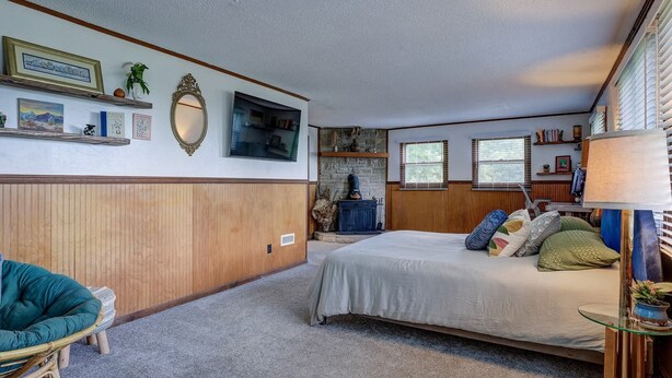 A bedroom with a bed, a chair, a fireplace, and a window. - Rhododendron Retreat— Dog-Friendly, Sauna, Mountain Views, Appalachian Trail (Roan Mountain)