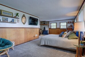 A bedroom with a bed, a chair, a fireplace, and a window.