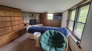 A room with a bed, a chair, a fireplace, and a window.