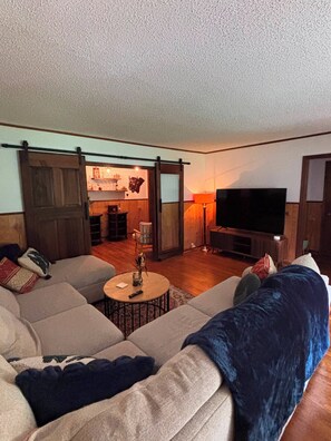 A living room with a sectional sofa, a coffee table, a TV, and a fireplace.