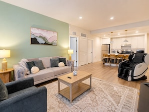 Un salon avec un canapé, une table basse et un tapis. Il y a un tableau au mur et une chaise dans un coin.