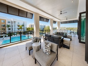 A spacious balcony with a pool, outdoor seating, and a view of neighboring buildings. - Luxury North Retreat with Pool and Gym (Naples)