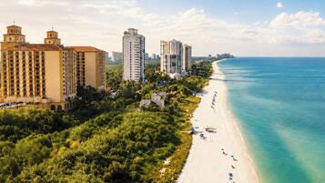 A coastal area with high-rise buildings, a beach, and dense greenery.