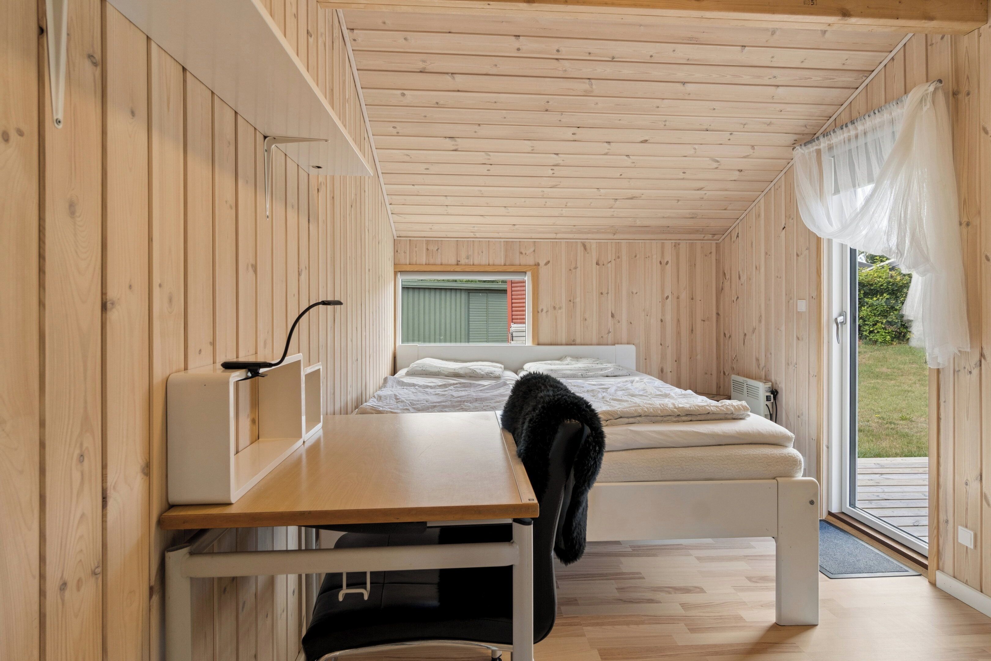 A compact room with a bed, a desk, and a window with blinds.