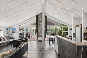 Ein großzügiger Wohnbereich mit hoher Decke, Kamin und Blick ins Freie.