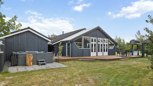 A two-story house with a patio area, a hot tub, and a covered outdoor seating area. - Large holiday home with spa and games room (Brovst)