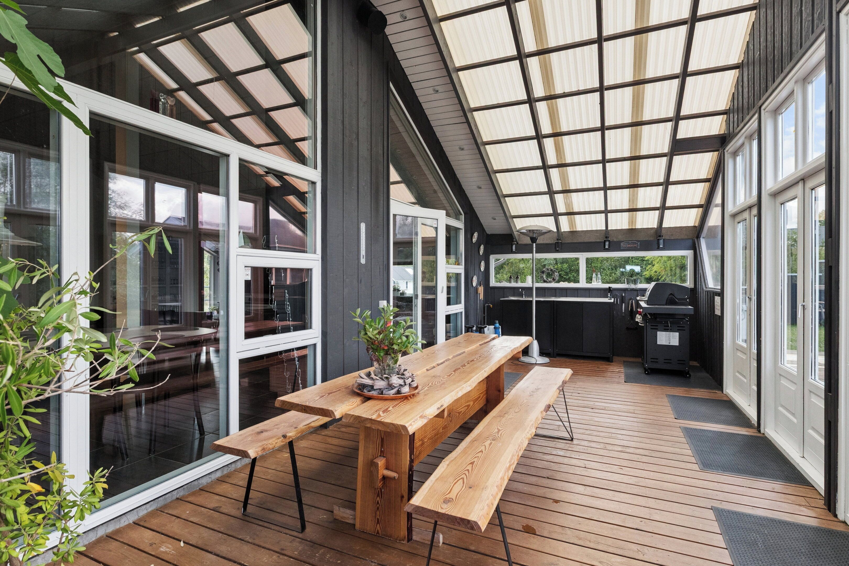 Une terrasse extérieure avec des bancs en bois et un espace barbecue.