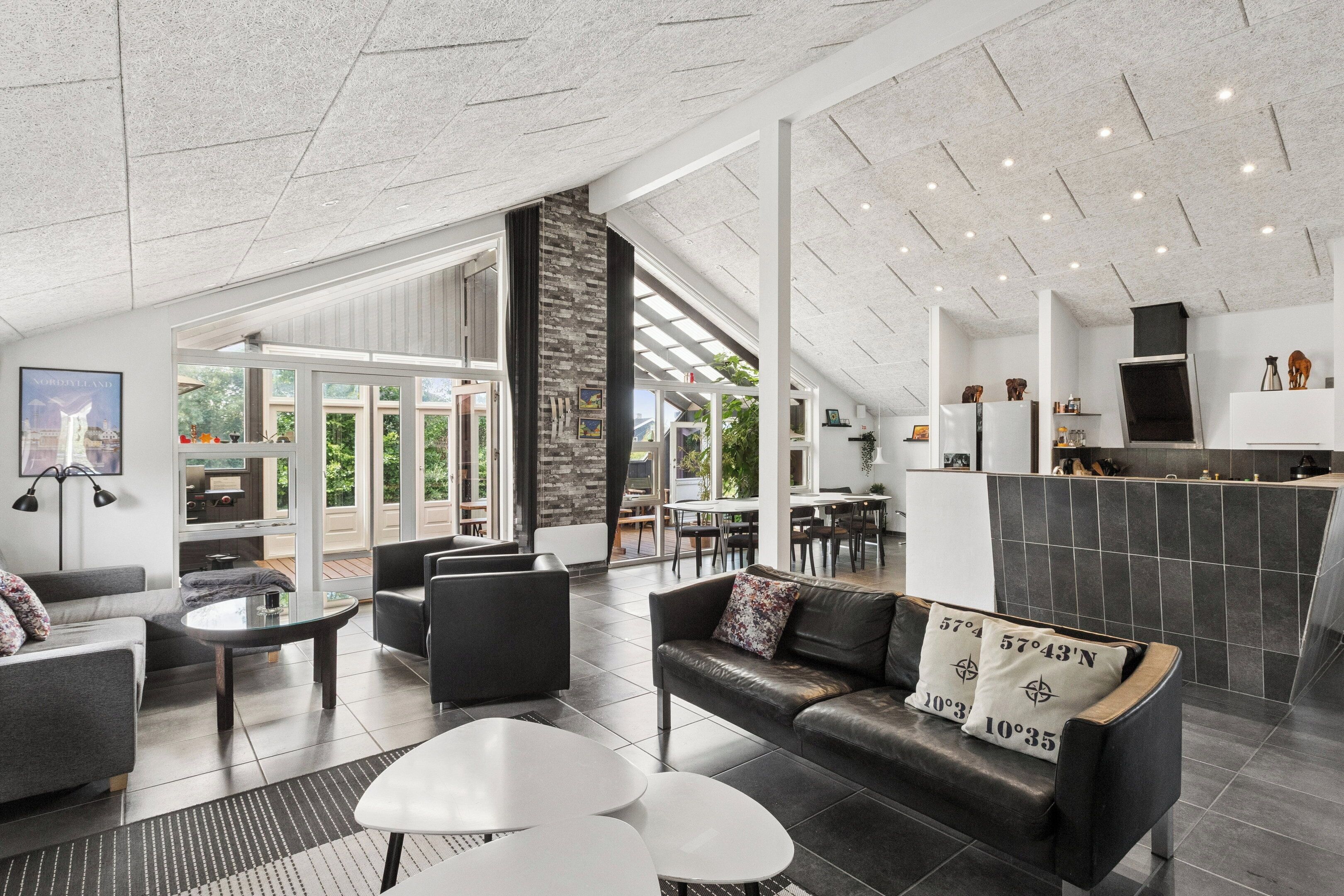 A modern interior with a seating area, a fireplace, and a view through large glass doors.