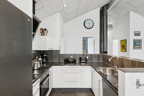 A modern kitchen with white cabinets, a black countertop, and a stainless steel sink. - Large holiday home with spa and games room (Brovst)
