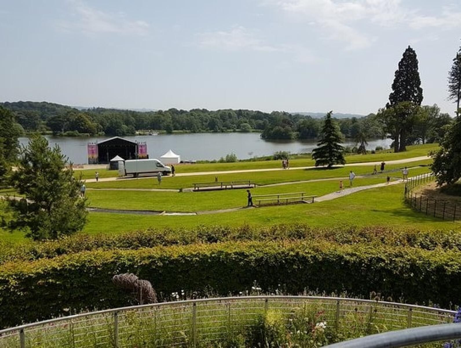A park with a lake, a fenced area, and a building with a white roof.