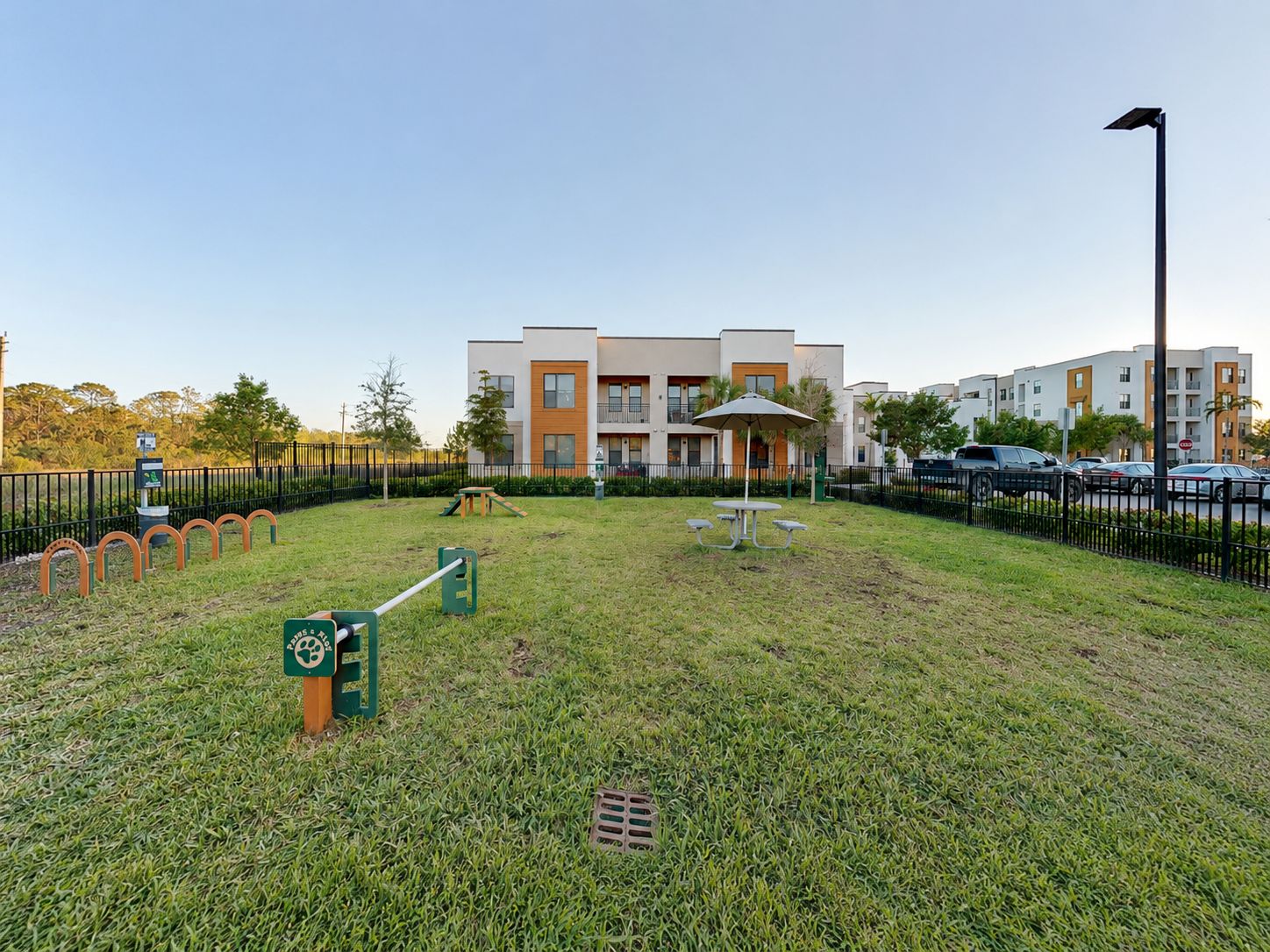 A fenced outdoor area with a picnic table, benches, and a playground.