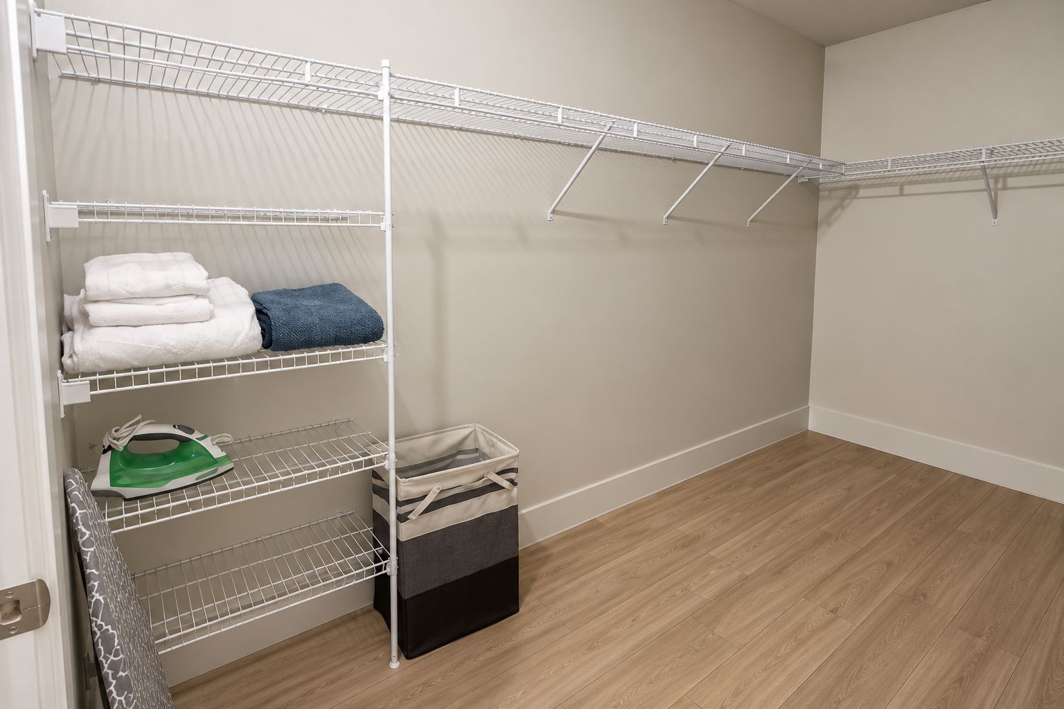 A storage closet with shelves for folded clothes, a hanging rack, and a storage bin.