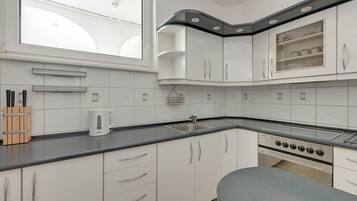 A modern kitchen with white cabinets, a black countertop, a built-in oven, and a window above the sink.