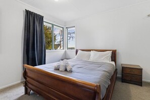 Ein Schlafzimmer mit einem hölzernen Bett, einem Nachttisch und einem Fenster mit Vorhängen.