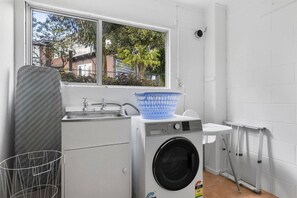 Ein kleiner Waschbereich mit Waschmaschine, Spüle und Fenster.