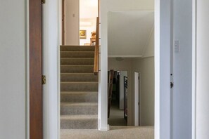 A carpeted staircase with a wooden handrail leading to a room with a door and a closet. - Family Haven, Lake Taupō Escape (Taupō)