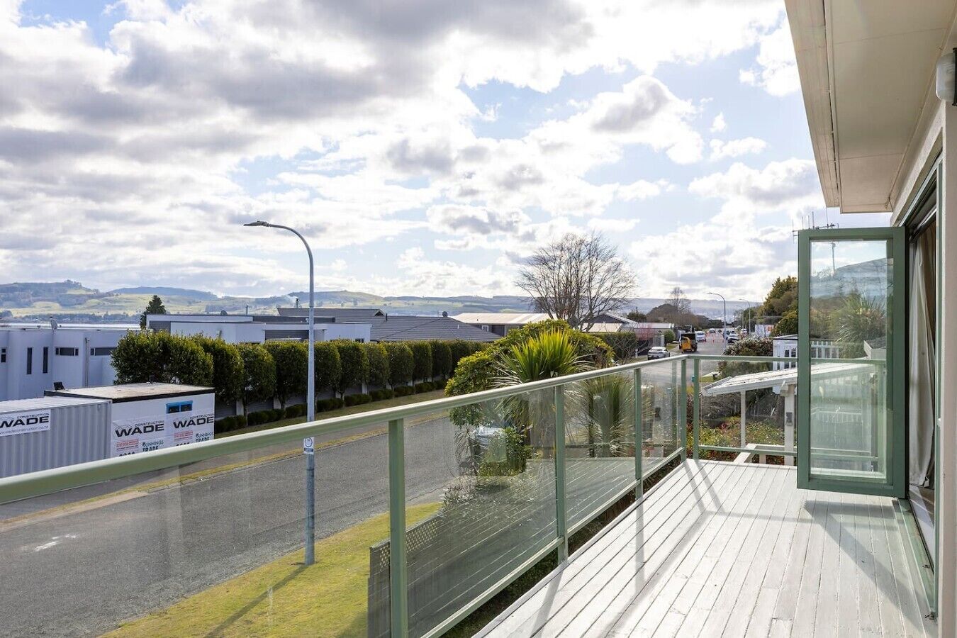 A balcony with a view of a road, industrial buildings, and a clear sky.