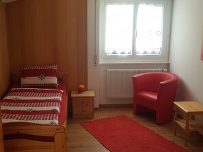 Ein Schlafzimmer mit einem Bett, einem roten Sessel, einem kleinen Tisch, einem Nachttisch und einem Fenster mit Blick.